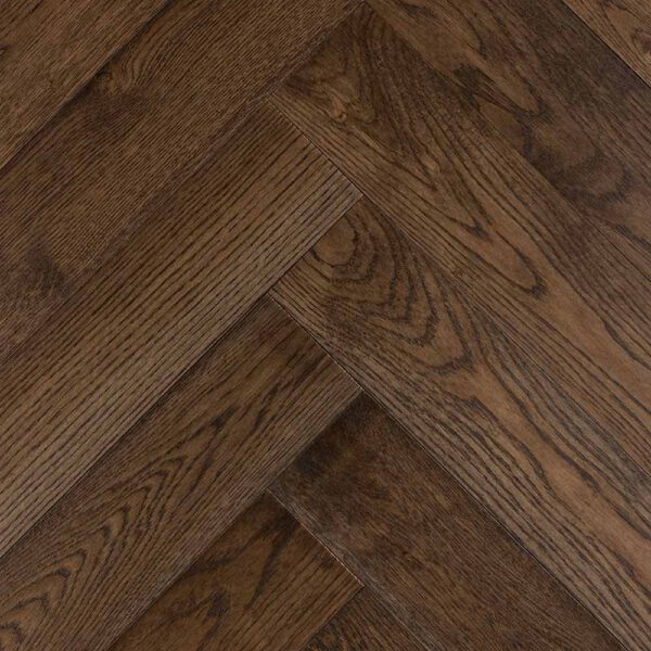 Zbliżenie na starą drewnianą podłogę ze wzorem w jodełkę.